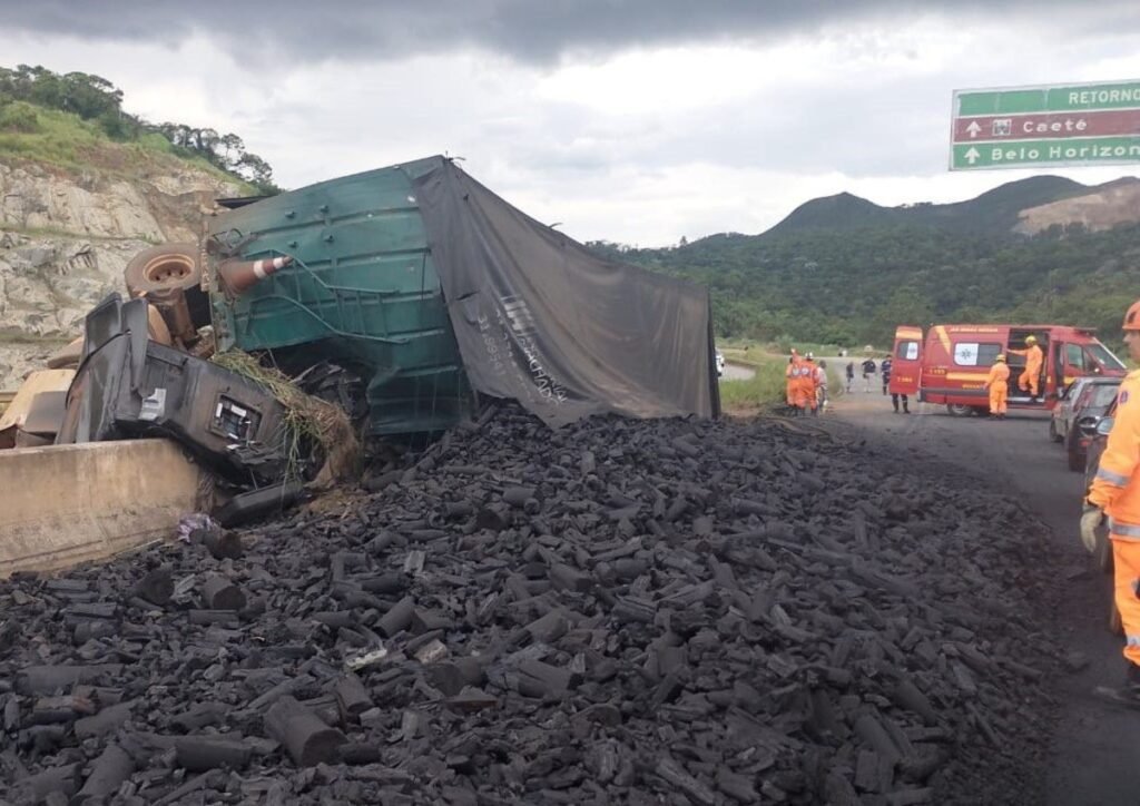 Carreta carregada de carvão tomba e fica pendurada em viaduto da BR-381; motorista morreu